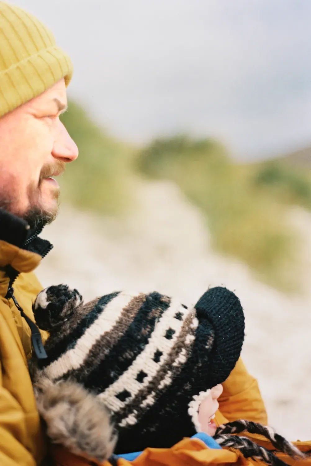 A parent and child wrapped up on a beach